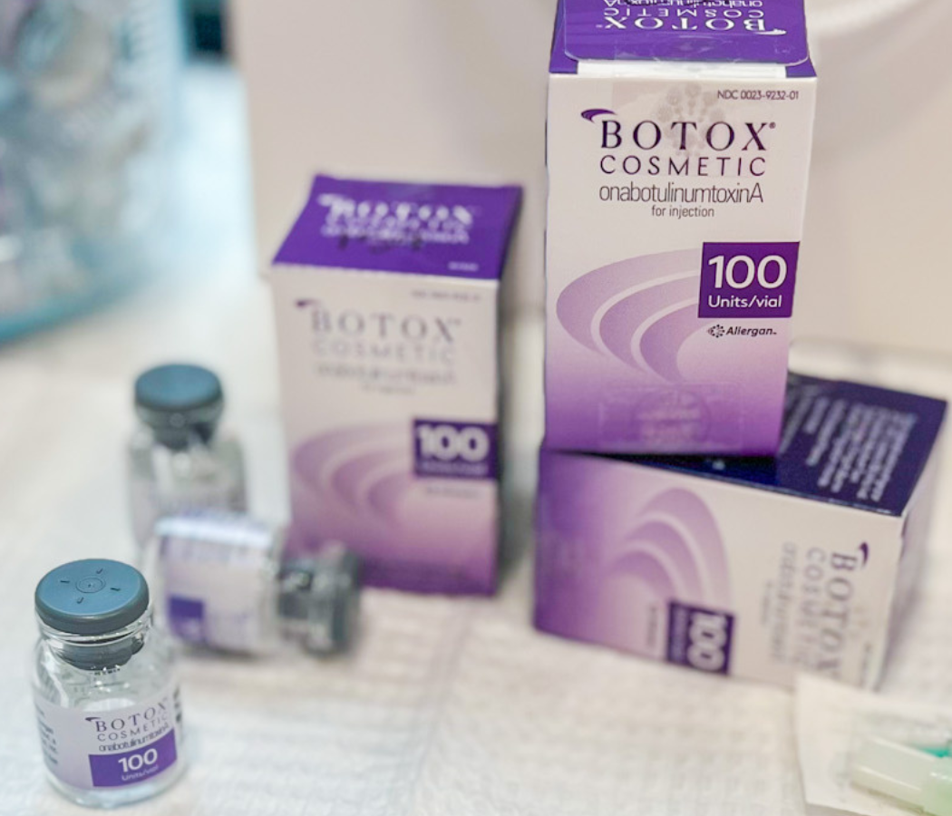 Image shows multiple vials and boxes of Botox Cosmetic, a product containing onabotulinumtoxinA for injection. Each vial is labeled with "100 Units" indicating the dosage. The packaging features a purple design with the Allergan logo. This image is relevant for discussions on cosmetic treatments, aesthetic procedures, and the use of Botox for reducing wrinkles and fine lines.