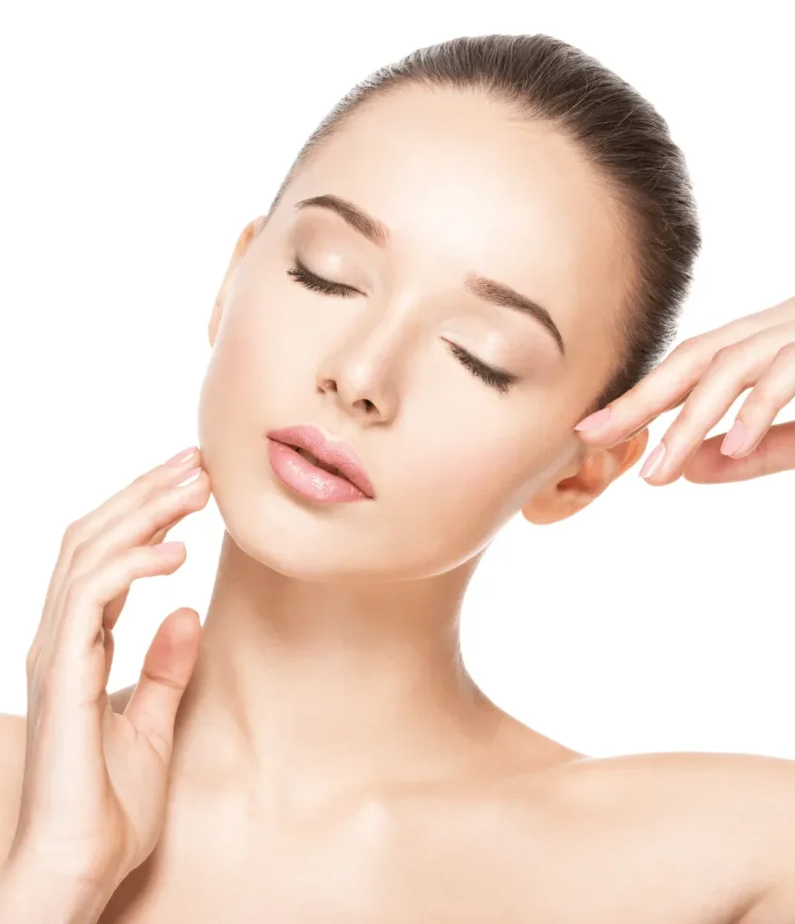Close-up of a woman with smooth skin, eyes closed, and a serene expression, gently touching her face with one hand while the other rests near her ear. The image features a clean, white background that highlights her natural beauty, showcasing a minimalist aesthetic ideal for skincare or beauty products. This visual representation emphasizes self-care and radiance, making it suitable for wellness and beauty-related content.