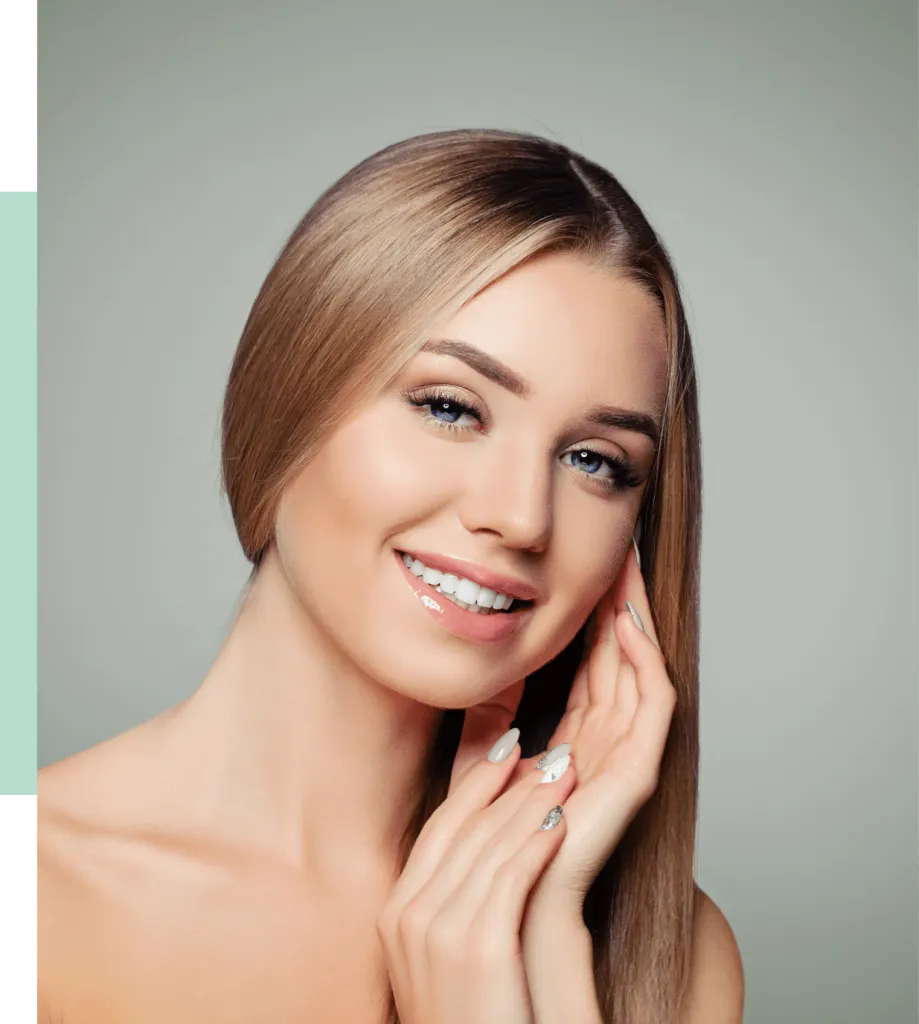 Portrait of a smiling woman with long, straight blonde hair and light blue eyes. She is gently touching her face with one hand while the other rests against her neck. The background is a soft gradient, enhancing her radiant complexion. The image conveys beauty and confidence, ideal for beauty and skincare promotions.