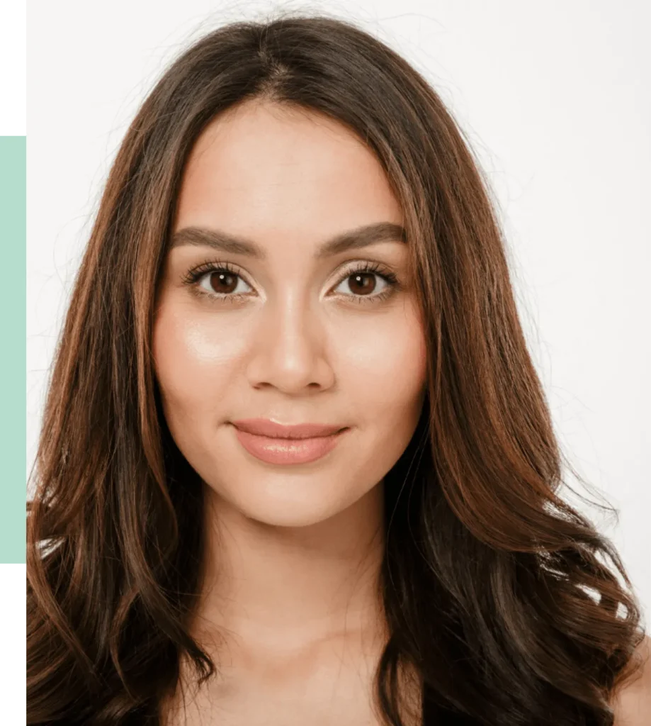 A close-up portrait of a woman with long, wavy brown hair and natural makeup. She has a warm smile and is looking directly at the camera against a light background. This image showcases beauty and confidence, ideal for beauty, fashion, or lifestyle content.