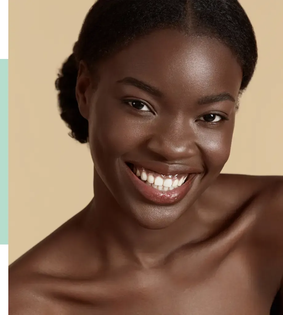 Smiling woman with dark skin and natural hair, showcasing a radiant smile and healthy teeth. She has a smooth complexion and is posed against a soft, neutral background. The image highlights her confident expression and natural beauty, emphasizing features such as her bright eyes and well-defined cheekbones. This portrait captures the essence of joy and positivity, making it ideal for beauty and wellness content.