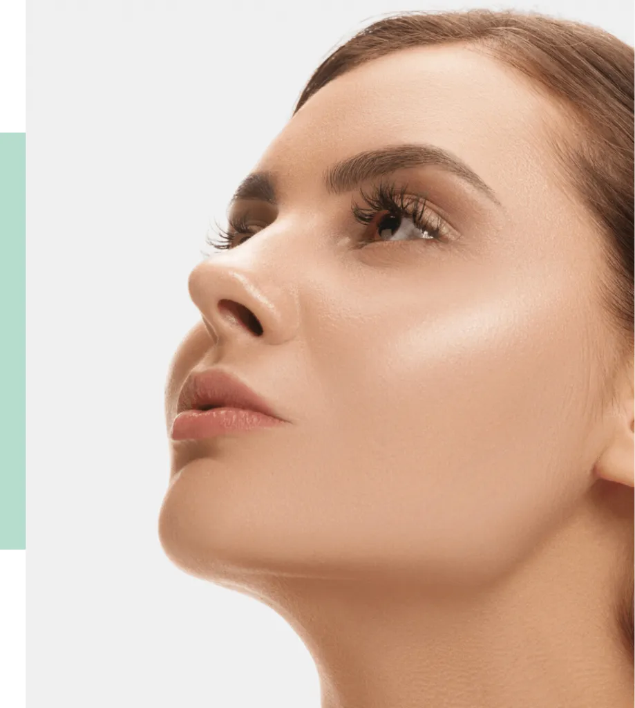 Close-up of a woman with flawless skin and defined features, showcasing her profile. She has long eyelashes and a subtle glow on her cheekbones, emphasizing a natural beauty look. The background is minimalistic, enhancing the focus on her face. This image represents skincare and beauty aesthetics, making it ideal for promoting beauty products or services.